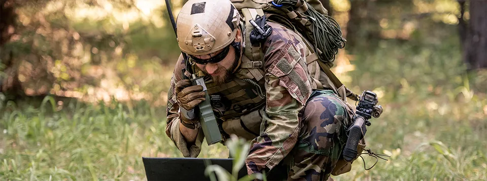 soldier-using-laptop-in-grassy-forest-environment-2026-03-09-03-22-35-sm